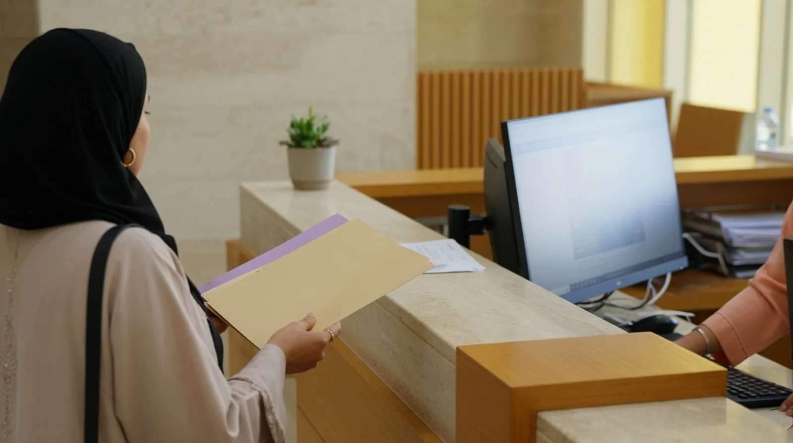 A parent handing an envelope of school documents across a Dubai school admissions counter