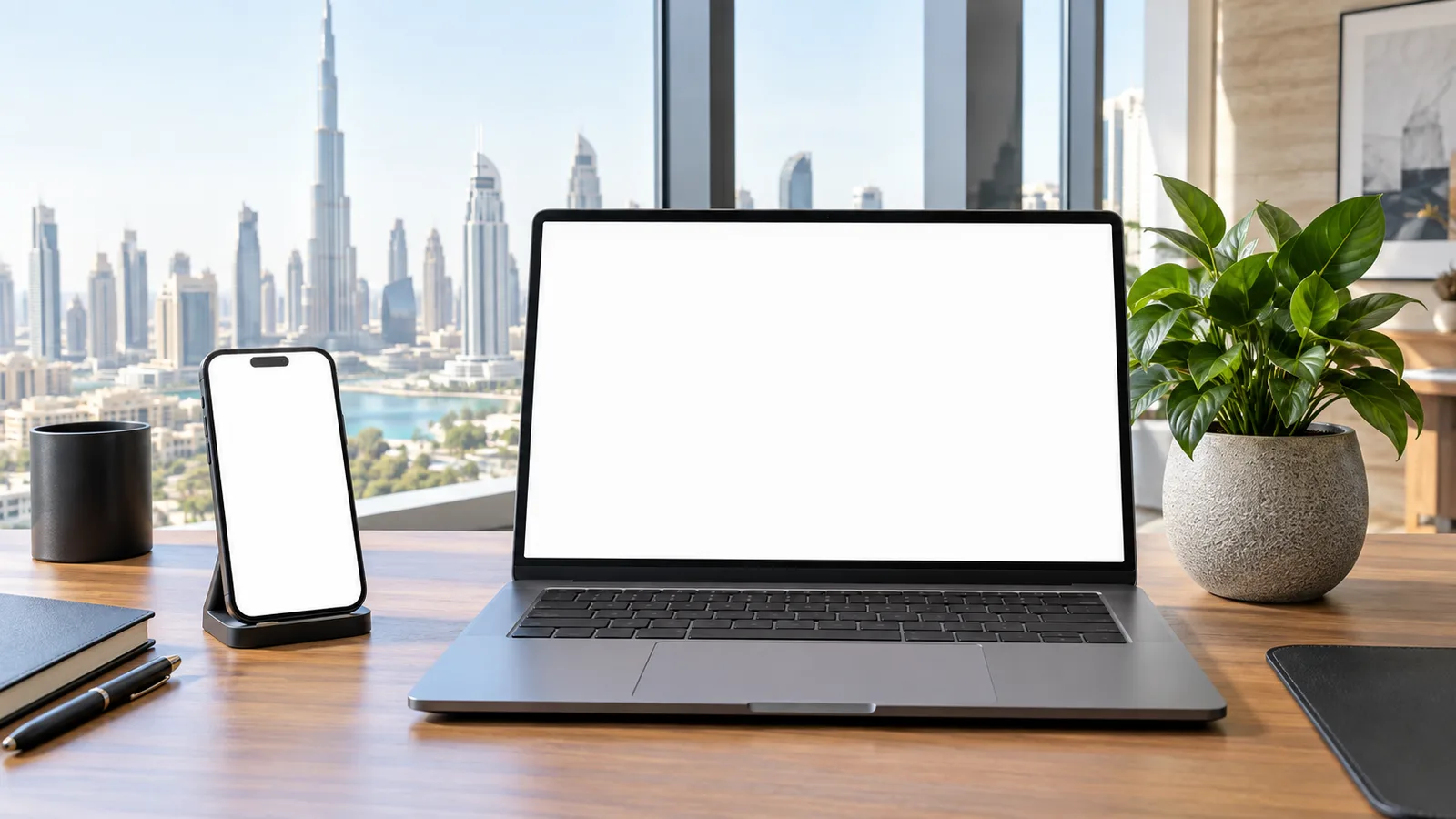 Phone held on a stand beside a laptop in a bright Dubai office